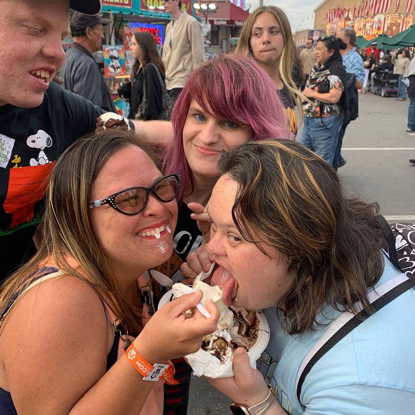 Friends sharing ice cream and laughing together at a fair
